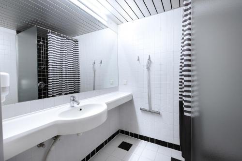 ein weißes Badezimmer mit einem Waschbecken und einem Spiegel in der Unterkunft Peoleo Hotell in Tallinn