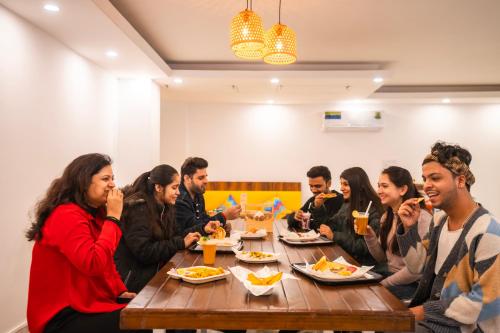Eine Gruppe von Menschen, die an einem Tisch sitzen und Essen essen. in der Unterkunft goSTOPS Gurugram in Gurgaon
