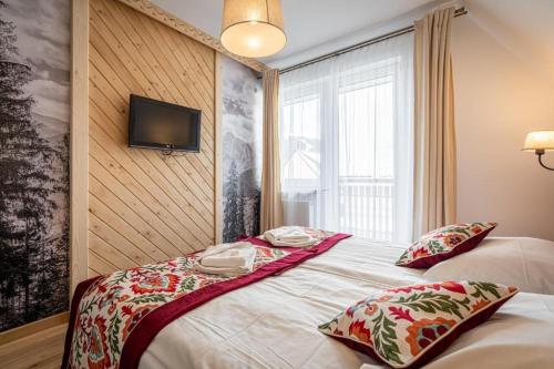 a bedroom with a bed and a tv on a wall at Pensjonat Dawidek in Zakopane