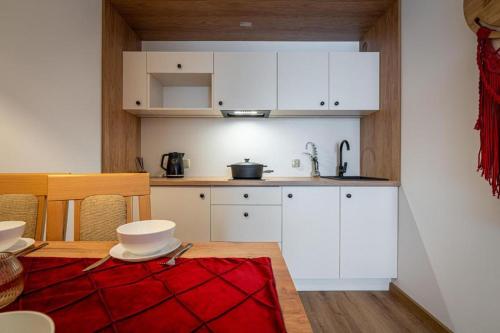 a kitchen with white cabinets and a red rug at Pensjonat Dawidek in Zakopane