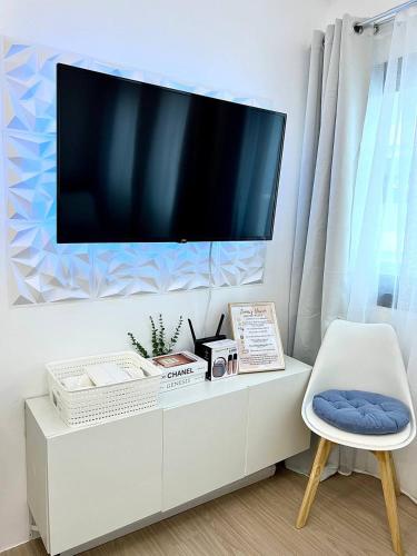 a tv on top of a white cabinet with a chair at Casa Luna Unit 1 in Manila