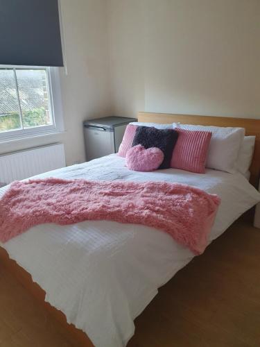 a bed with pink and white sheets and pillows at Comfy bedroom D in London