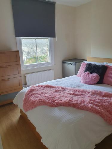 a bedroom with a bed with a pink blanket on it at Comfy bedroom D in London