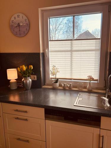 a kitchen with a sink and a window with a clock at Ferienhaus Dycke 6 in Zudar