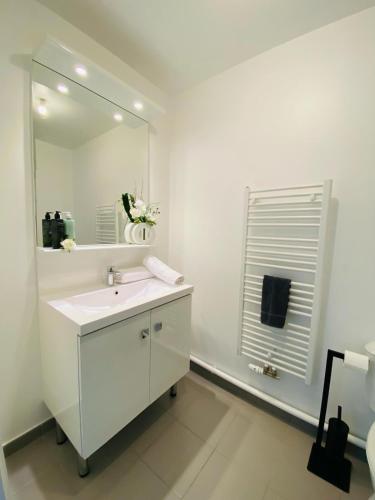 een witte badkamer met een wastafel en een spiegel bij L'Escale Cosy - Disneyland Paris in Serris