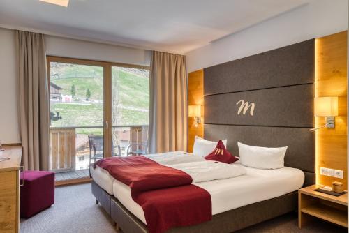 a hotel room with a bed and a large window at Mallaun Hotel.Erlebnis in See