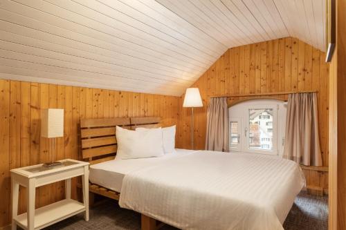 łóżko w pokoju z drewnianymi panelami w obiekcie Krone by b-smart w mieście Bad Ragaz