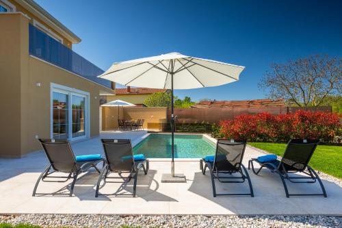 a patio with a table and chairs and an umbrella at Beautiful Villa Onit with outdoor pool in Vizinada in Ferenci