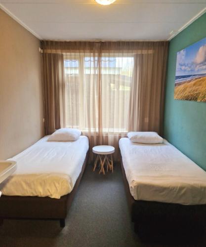 a hotel room with two beds and a window at Budget Hotel Koogerend in Den Burg