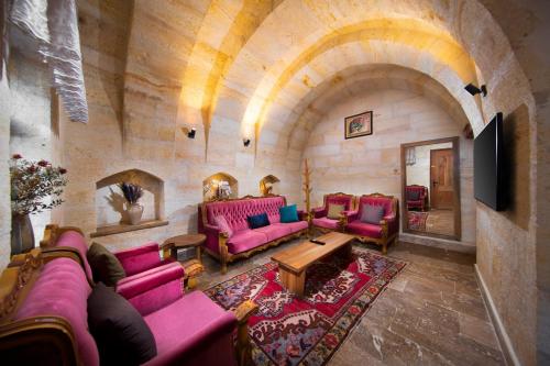 a living room with pink couches and a stone wall at Ayazma Cave Hotel in Urgup