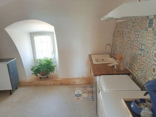 uma cozinha com um lavatório, uma mesa e uma janela em Le Clos de Soulages gîte 2 pers em Palmas