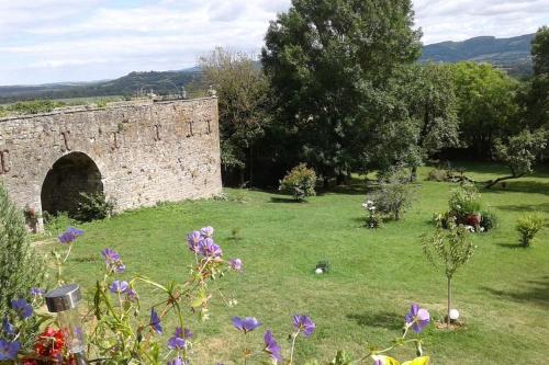 um jardim com uma parede de pedra e flores em Le Clos de Soulages gîte 2 pers em Palmas