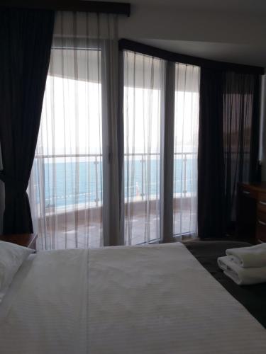 a bedroom with a large bed and large windows at Apartman AidaLux in Bijela Glavica
