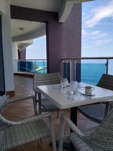 a table and chairs on a balcony with the ocean at Apartman AidaLux in Bijela Glavica
