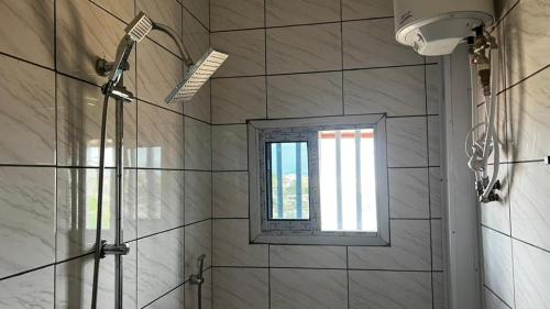 La salle de bains est pourvue d'une douche et d'une fenêtre. dans l'établissement Magistral apparts, à Yaoundé