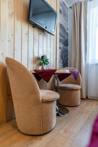 a living room with two chairs and a table and a tv at Pensjonat Dawidek in Zakopane