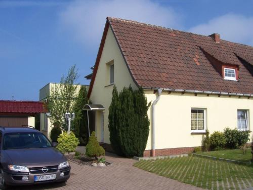 una casa blanca con un coche aparcado en la entrada en Comfortable Apartment near Seabeach in Rerik, en Rerik