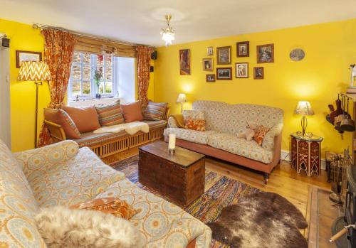 ein Wohnzimmer mit gelben Wänden und Sofas in der Unterkunft Sausage Cottage Oakford in Oakford