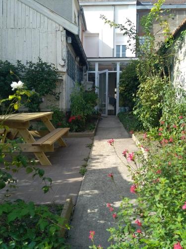 - une table de pique-nique en bois à côté d'un bâtiment fleuri dans l'établissement La petite pétillante, à Reims