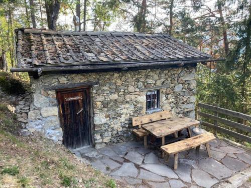 a small stone building with a bench and a table at Sturmhof in Chiusa