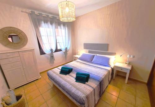 a bedroom with a bed with two green chairs on it at Buen Camino El Cotillo in El Cotillo