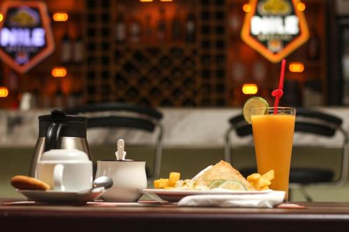 a table with a plate of food and a glass of orange juice at Excelsis Garden Hotels - Kampala in Kampala