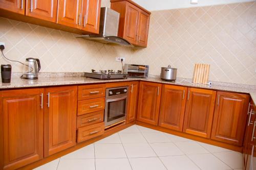 a kitchen with wooden cabinets and a stove at Oasis Village and Club in Dar es Salaam