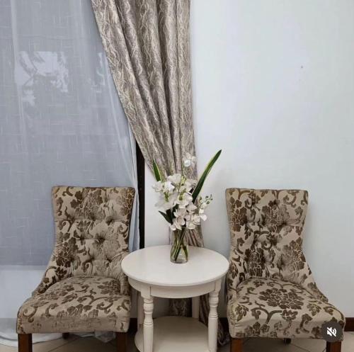 dos sillas y una mesa con un jarrón de flores en Oasis Village and Club en Dar es Salaam