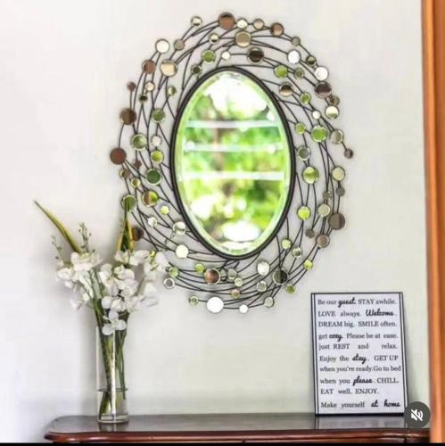 a mirror on a wall with a vase of flowers at Oasis Village and Club in Dar es Salaam