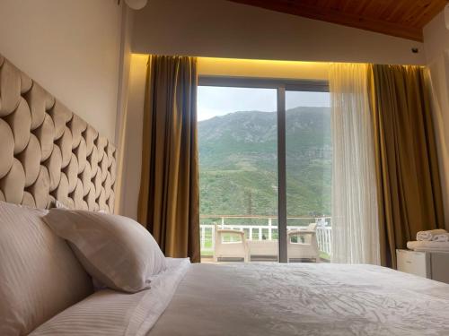een slaapkamer met een bed en een groot raam bij Guest-Room Zoi&Teri in Tepelenë