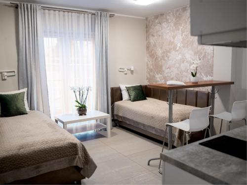 a bedroom with two beds and a desk and a window at Apartamenty Pyskowice in Pyskowice