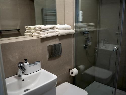 a bathroom with a sink and a shower with towels at Apartamenty Pyskowice in Pyskowice
