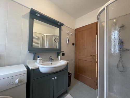ein Bad mit einem Waschbecken und einer Dusche mit einem Spiegel in der Unterkunft 094 Trilocale, pinzolo in Pinzolo