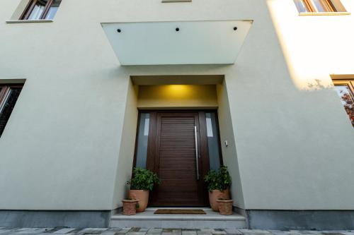 a front door of a white building with two potted plants at House "Mediterrian spirit" with jacuzzi in Zadar in Zadar