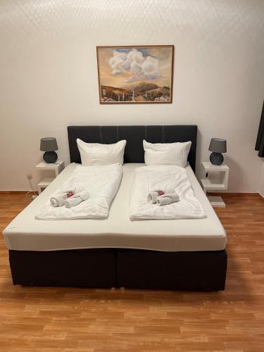 uma cama grande com lençóis brancos e almofadas em Harzglück em Ballenstedt