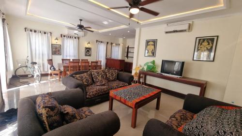 a living room with couches and a tv and a table at Phasouk Viengmai Villa in Luang Prabang