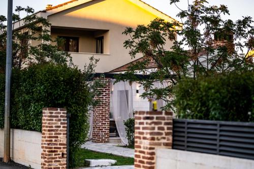 a white house with a brick wall and trees at House "Mediterrian spirit" with jacuzzi in Zadar in Zadar