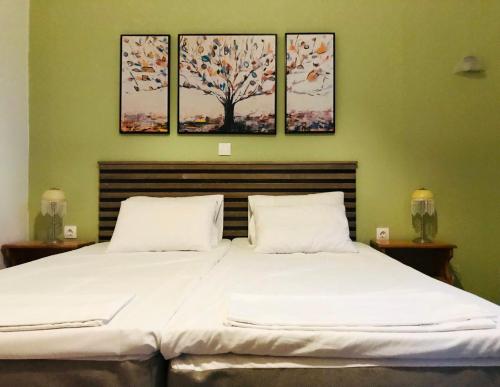 a bedroom with a large bed with three paintings on the wall at green house in Sfakerá