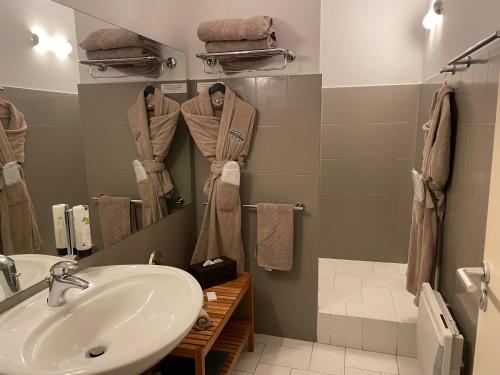 a bathroom with a sink and a shower with towels at Logis Hôtel de France & Restaurant Pamiers in Pamiers