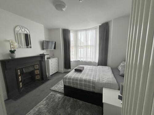1 dormitorio con cama, chimenea y espejo en Copperfield Homestay en Cardiff