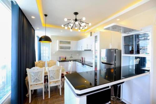 a kitchen with white cabinets and a black counter top at Empress Dalat - Sky View Hotel in Da Lat
