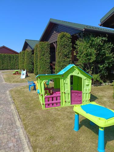 uma casa de brincar e um trampolim num quintal em Domki BIAŁA MEWA em Wicie