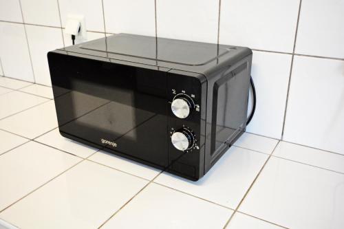 a black toaster oven sitting on a tiled floor at Twój Hostel Klimczoka 7 in Katowice