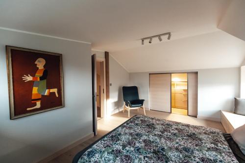 1 dormitorio con 1 cama y una pintura en la pared en Jaunkapteiņi, en Dzeņi