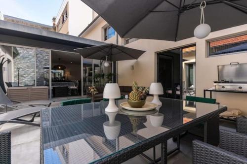 une table à manger avec un parasol sur une terrasse dans l'établissement Maison de 250 m2 avec SPA à Arcachon, à Arcachon