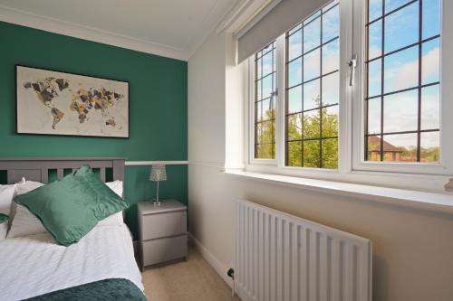 um quarto com paredes verdes, uma cama e janelas em Cosyhome ideal for professionals em Barrow upon Humber
