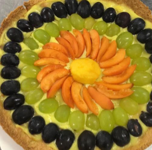 a fruit pizza with carrots and grapes on a plate at Casa Oliva borgo del Benessere Olistico in Bargni