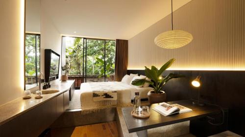 a bedroom with a bed and a desk and a window at Titik Dua in Ubud