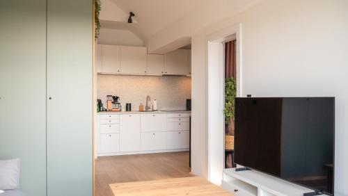 a kitchen with white cabinets and a flat screen tv at Apartament SUNSET SurfingBird Dźwirzyno in Dźwirzyno