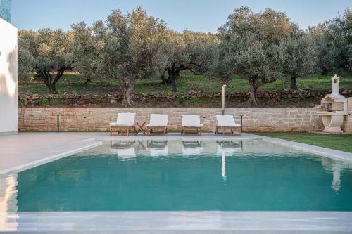 a swimming pool with two chairs and a fountain at Villa Zefyros With Sea View in Plataniás